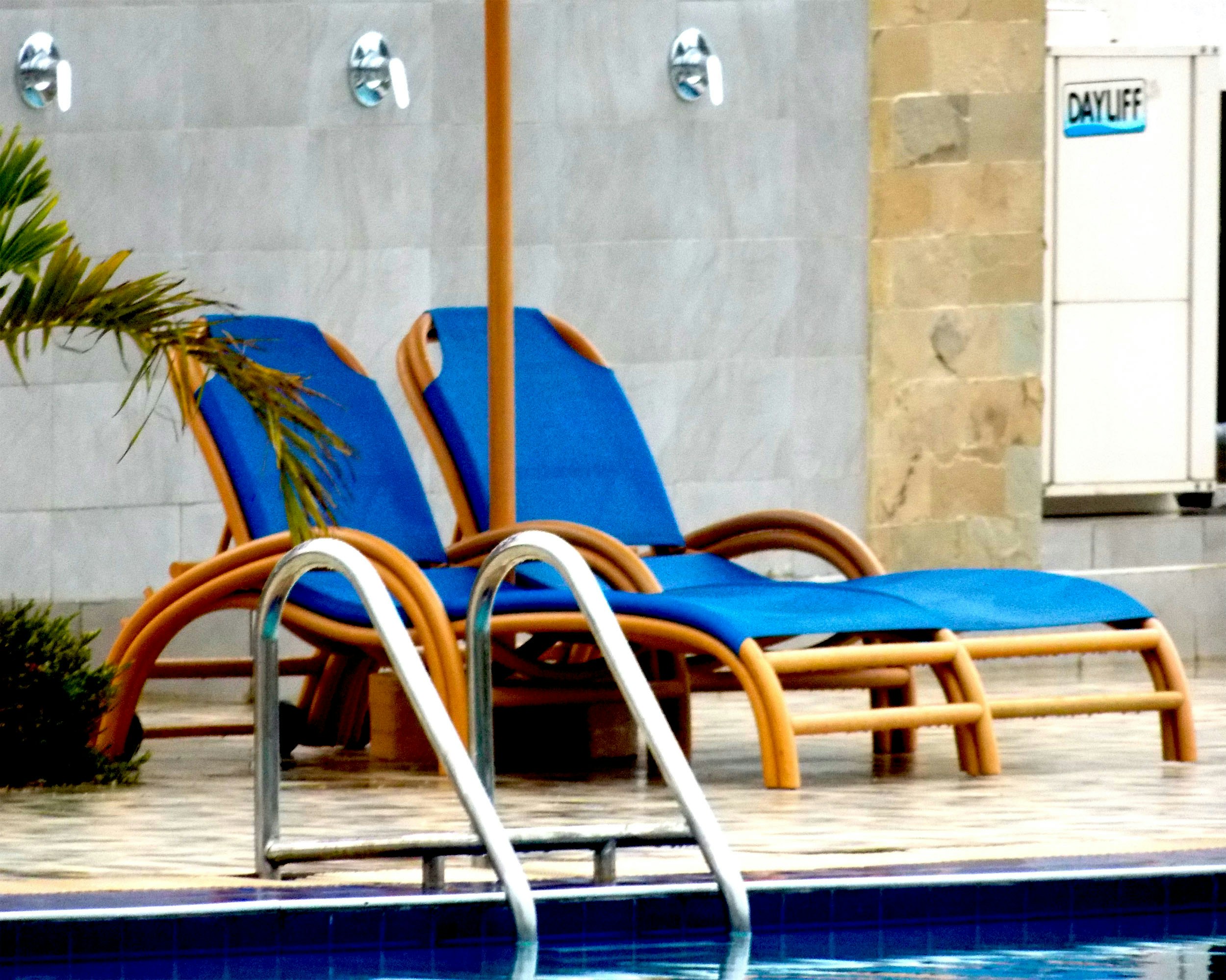 blue and white lounge chairs near swimming pool